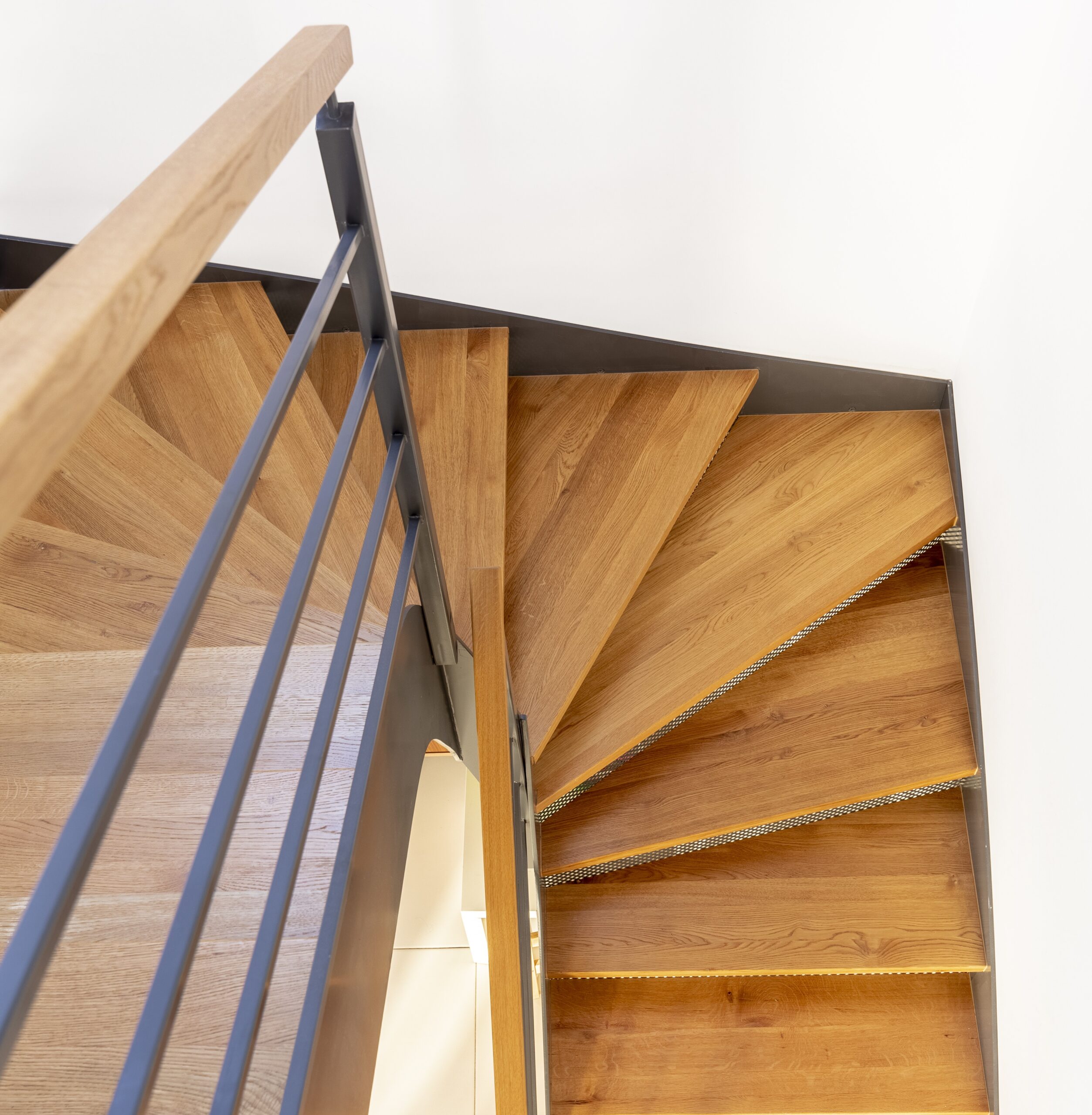Wooden staircase with ornate railing and curtains